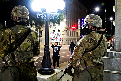 Soldiers with the North Carolina Army National Guard’s 105th Military Police Battalion stand guard in a city street, ensuring that a protester is able to practice her 1st Amendment rights in Raleigh, North Carolina, May 31.